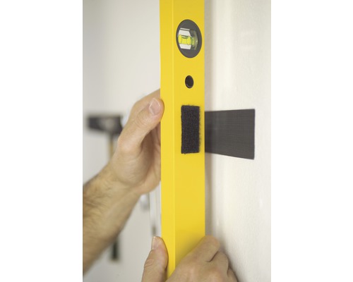 Un niveau à bulle jaune est aligné sur un mur.