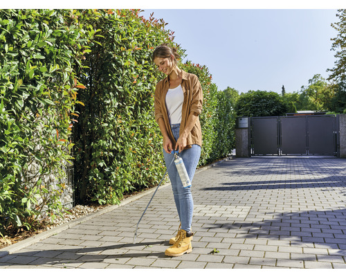 Eine Frau verwendet einen Gasbrenner zur Unkrautbekämpfung im Garten.