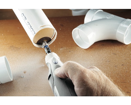 Une personne coupe un tuyau en plastique avec un outil multifonction.