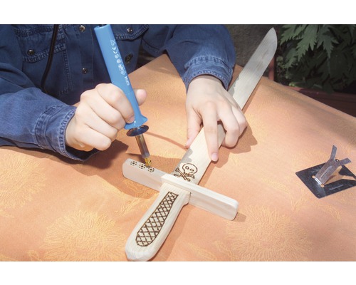 Eine Person verziert ein Holzschwert mit einem Brennkolben.