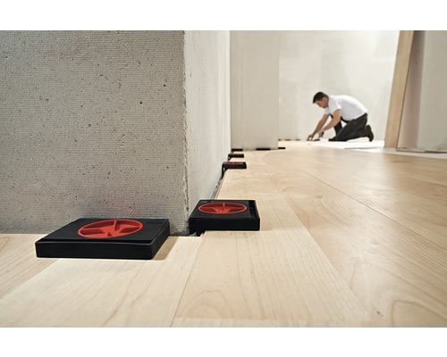 Pose de stratifié avec des cales d''écartement entre le mur et le sol