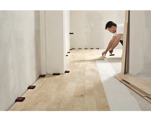 Pose de stratifié avec des outils et des entretoises dans une pièce.