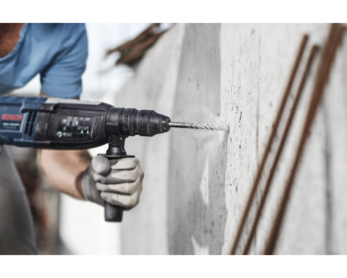 Mann bohrt Loch in Betonwand mit Bohrhammer