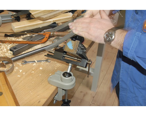 Handwerker bearbeitet Werkstück im Schraubstock mit einer Feile auf einer Werkbank