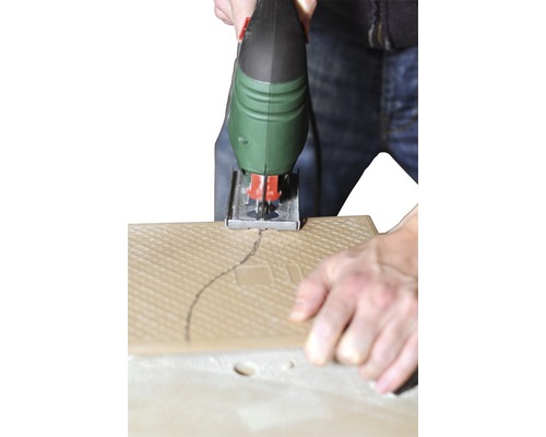 Une scie sauteuse coupe un carreau le long d''une ligne tracée.