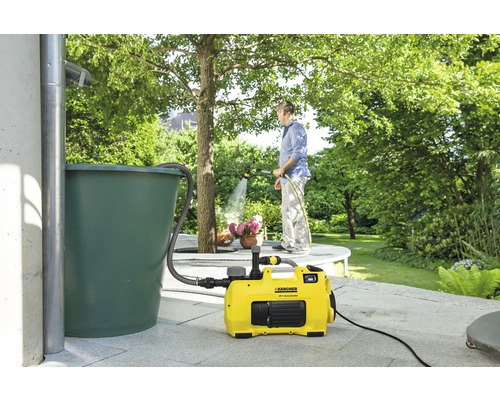 Jardin avec récupérateur d''eau de pluie, surpresseur et personne arrosant des plantes
