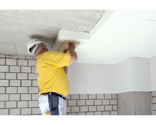 Artisan installant des panneaux isolants au plafond à l''aide d''une taloche pour l''isolation thermique.