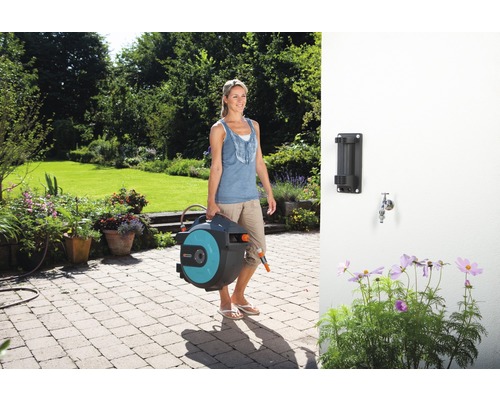 Frau trägt eine Schlauchtrommel im Garten