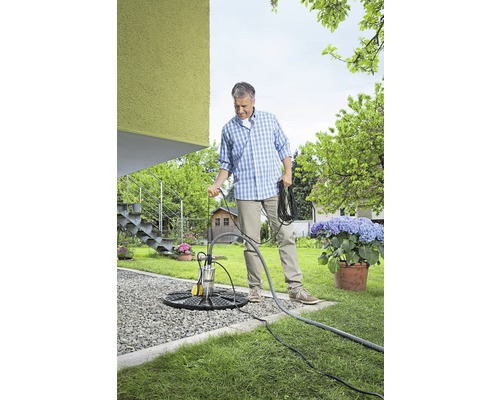 Ein Mann bereitet eine Tauchpumpe im Garten für den Einsatz vor.