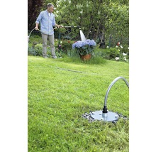 Homme arrosant des fleurs avec un tuyau d''arrosage et une prise d''eau de jardin