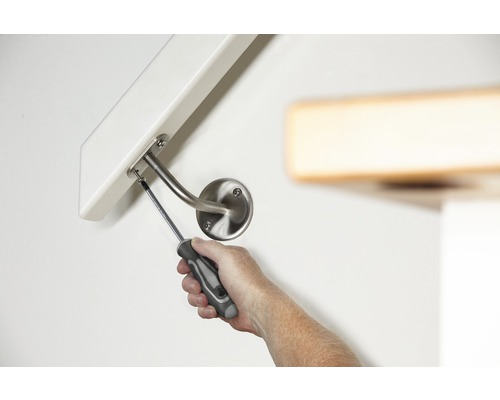 Eine Person montiert ein Geländer mit einem Schraubenzieher an einer Wand.