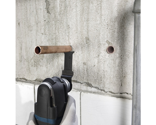 Outil multifonction coupant un tuyau en cuivre sur un mur