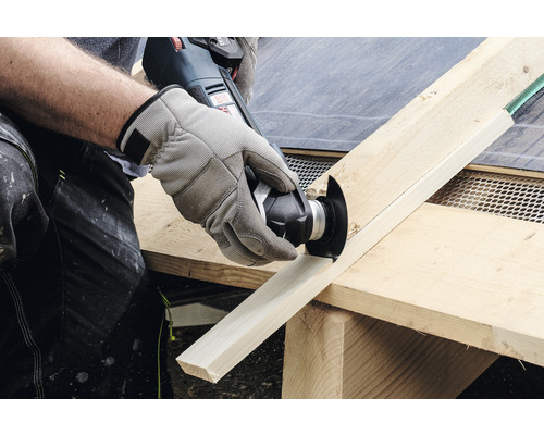 Eine Person schneidet mit einem Multifunktionswerkzeug ein Holzbrett.