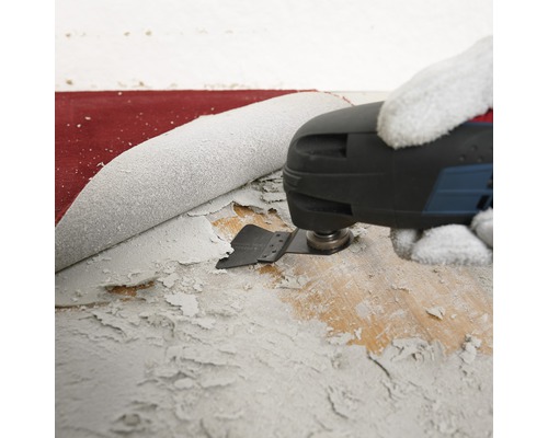 Outil multifonction oscillant en train d''enlever de la peinture sur une surface en bois.