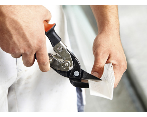 Eine Person schneidet mit einer Blechschere ein Metallstück.