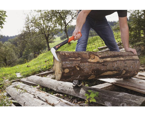 Un homme fend un tronc d''arbre avec une hache à fendre à l''extérieur.