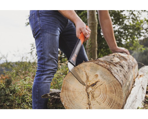 Une scie à main coupe un tronc d''arbre à l''extérieur.