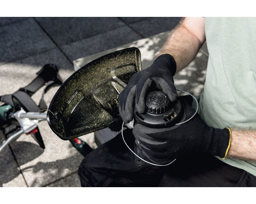 Une personne remplace la bobine d''un coupe-bordures.