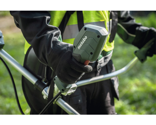 Une personne tient la poignée d''un coupe-bordure de la marque Metabo.