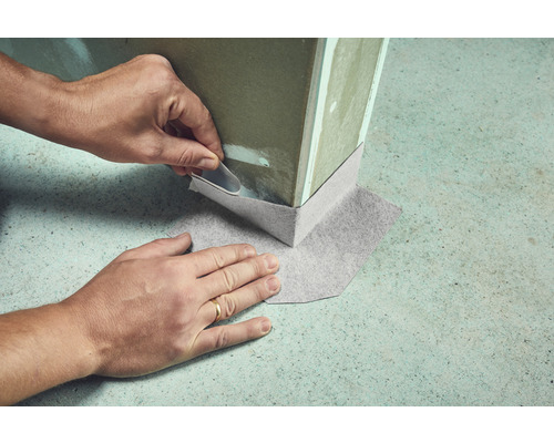 Vue détaillée de la pose d''une bande d''étanchéité au pied d''un mur à l''intérieur