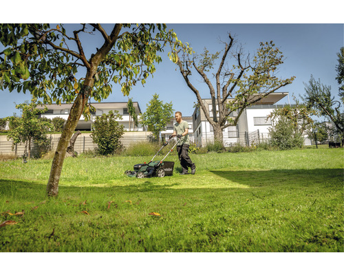 Homme tondant la pelouse avec une tondeuse à gazon dans le jardin.