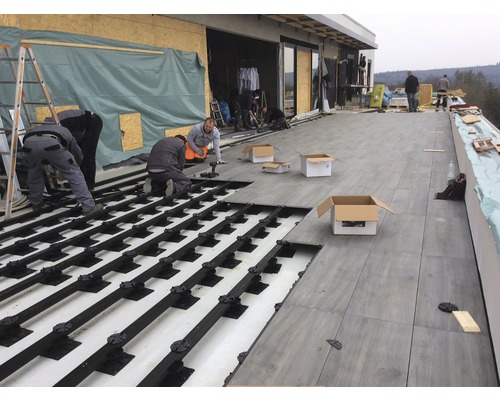 Pose de dalles de terrasse sur système de plots par des artisans