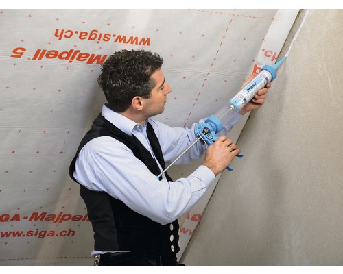 Un homme scelle un mur avec un pistolet à cartouche.