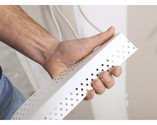 Une main tient un profilé de protection d''angle pour les travaux de plâtrage.
