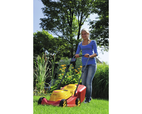 Une femme utilise une tondeuse à gazon dans le jardin.