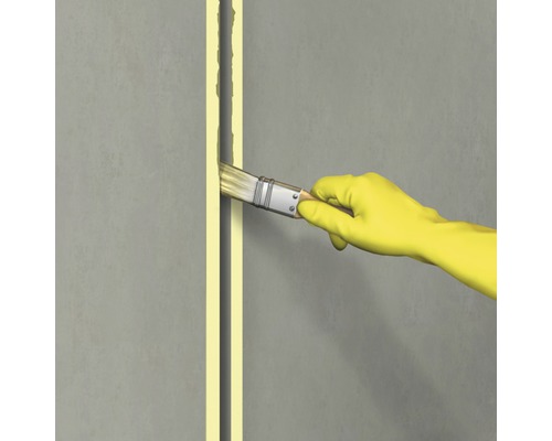 Une personne portant des gants utilise un pinceau pour sceller un joint.