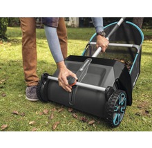 Une personne utilise un ramasse-feuilles Gardena sur une pelouse avec des feuilles.