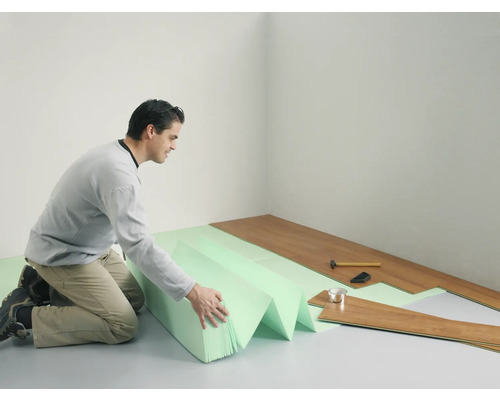 Homme posant un sol stratifié avec isolation phonique