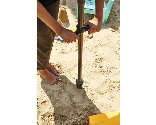 Une personne perce un trou dans le sable avec une tarière.