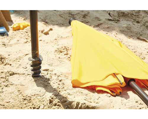 Parasol jaune avec ancrage au sol dans le sable