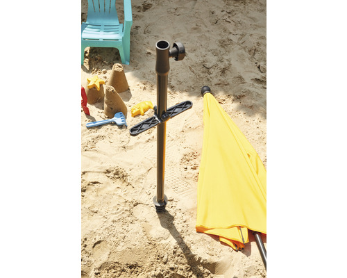 Scène de sable avec pied de parasol, jouets et chaise longue dans le sable