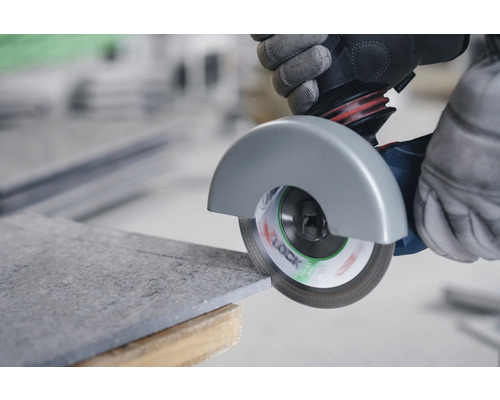 Une personne coupe une tuile avec une meuleuse d''angle