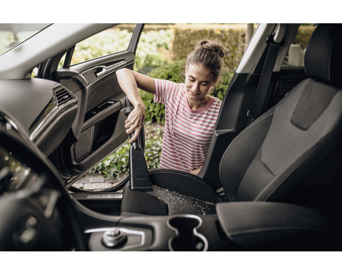 Femme passe l''aspirateur sur les sièges auto avec un aspirateur