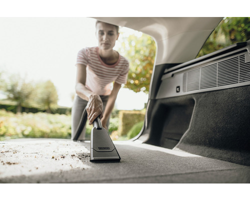 Femme aspire le coffre de voiture avec un aspirateur