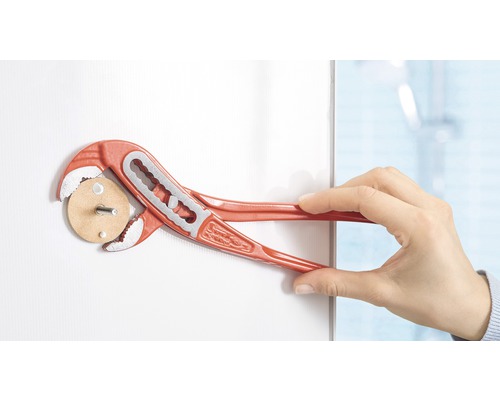 Une main tient une clé serre-tube sur une aide au montage.