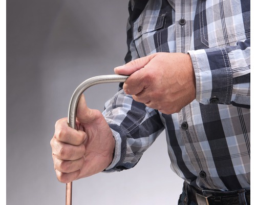 Une personne plie un tuyau métallique flexible.