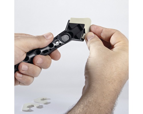 Une main fixe un tampon d''étanchéité sur un grattoir à joints.