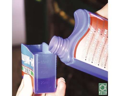 Le réducteur de pH ou de KH JBL est versé dans un gobelet doseur