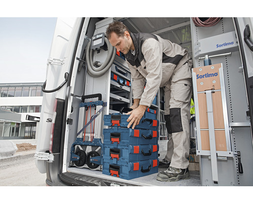 Artisan dans une camionnette rangeant des boîtes à outils et un chariot à outils Sortimo