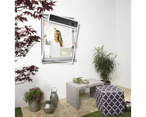 Frau montiert Insektenschutzgitter an einem Fenster im Aussenbereich