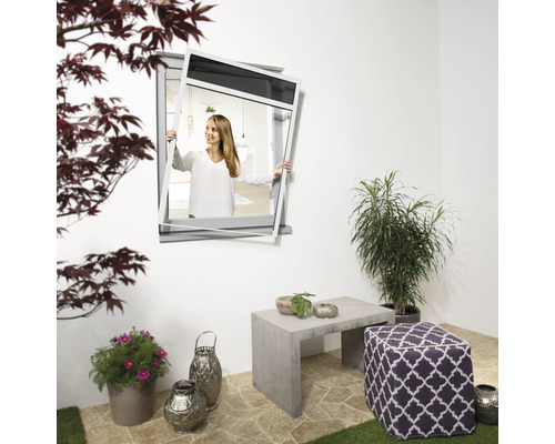 Frau montiert Insektenschutzgitter vor einem Fenster