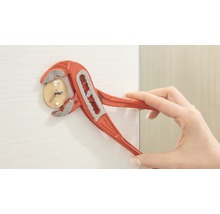 Eine Person benutzt eine Rohrzange, um einen Holzdübel mit Schraube in eine weisse Oberfläche zu drehen.