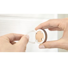 Eine Hand entfernt die Schutzfolie von einem runden Möbelknopf zur Montage.