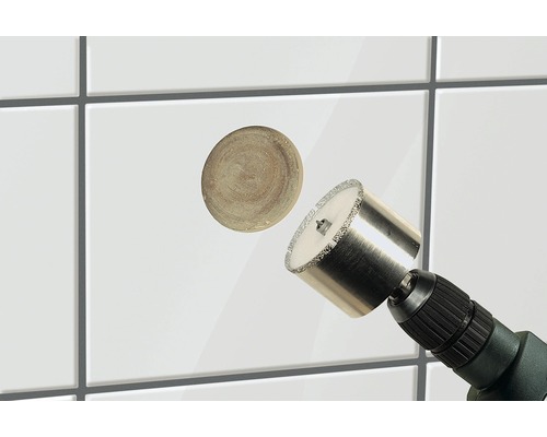 Scie cloche à carrelage en cours d''utilisation sur des carreaux blancs