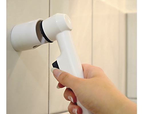 Brosse de nettoyage électrique avec support mural dans une main