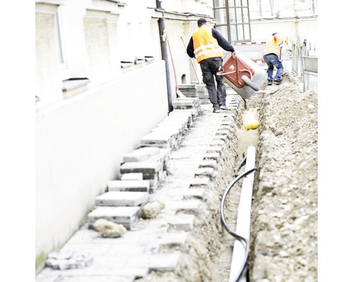 Ouvriers travaillant sur une tranchée avec des tuyaux et des pavés.